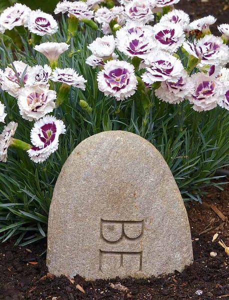 Garden rock with flowers that says "BE"