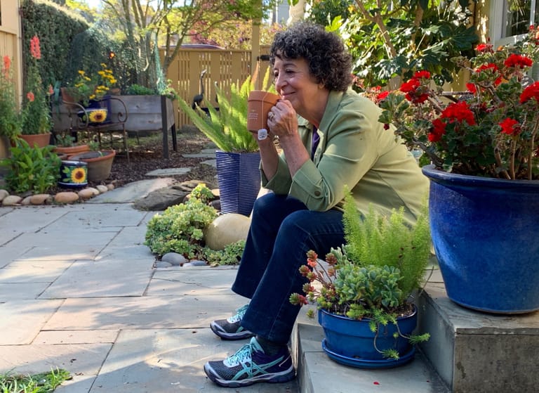 Toni Gattone in her garden sipping tea